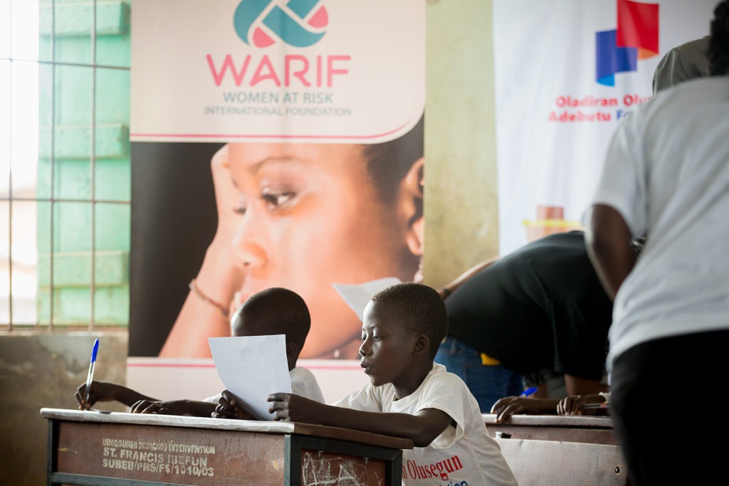 Little boy in a white shirt reading from a white A4 paper
