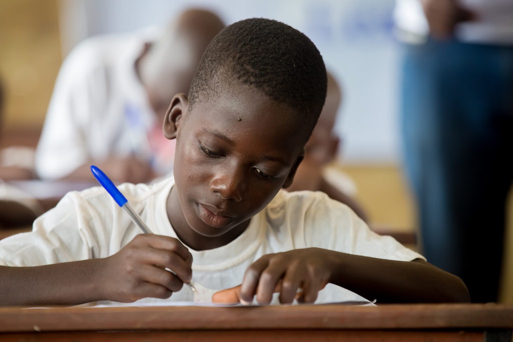 Little boy in a white shirt writing in a notebook