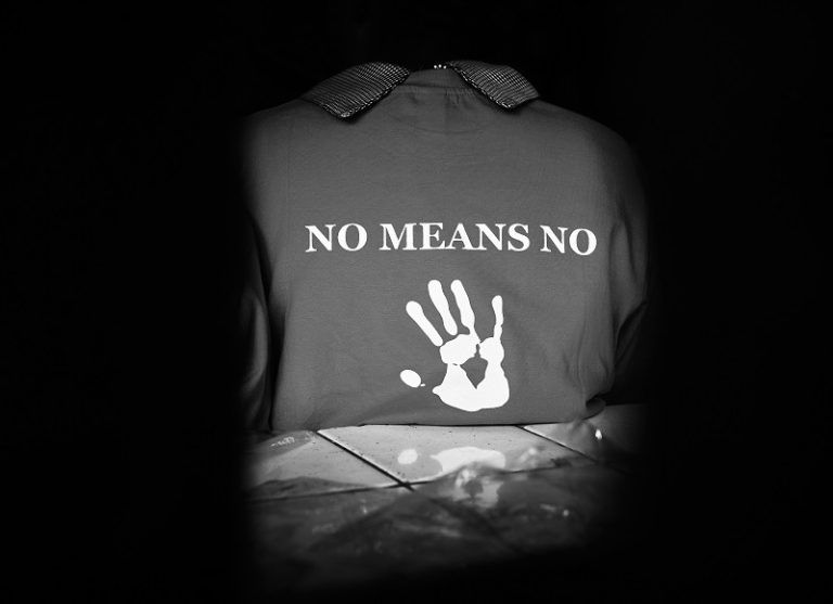Picture of the back of a girls shirt that reads "NO MEANS NO" with a hand print at the bottom of the shirt.